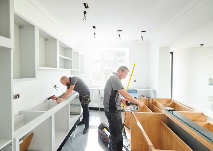 Two work men installing a new kitchen in a regular home
